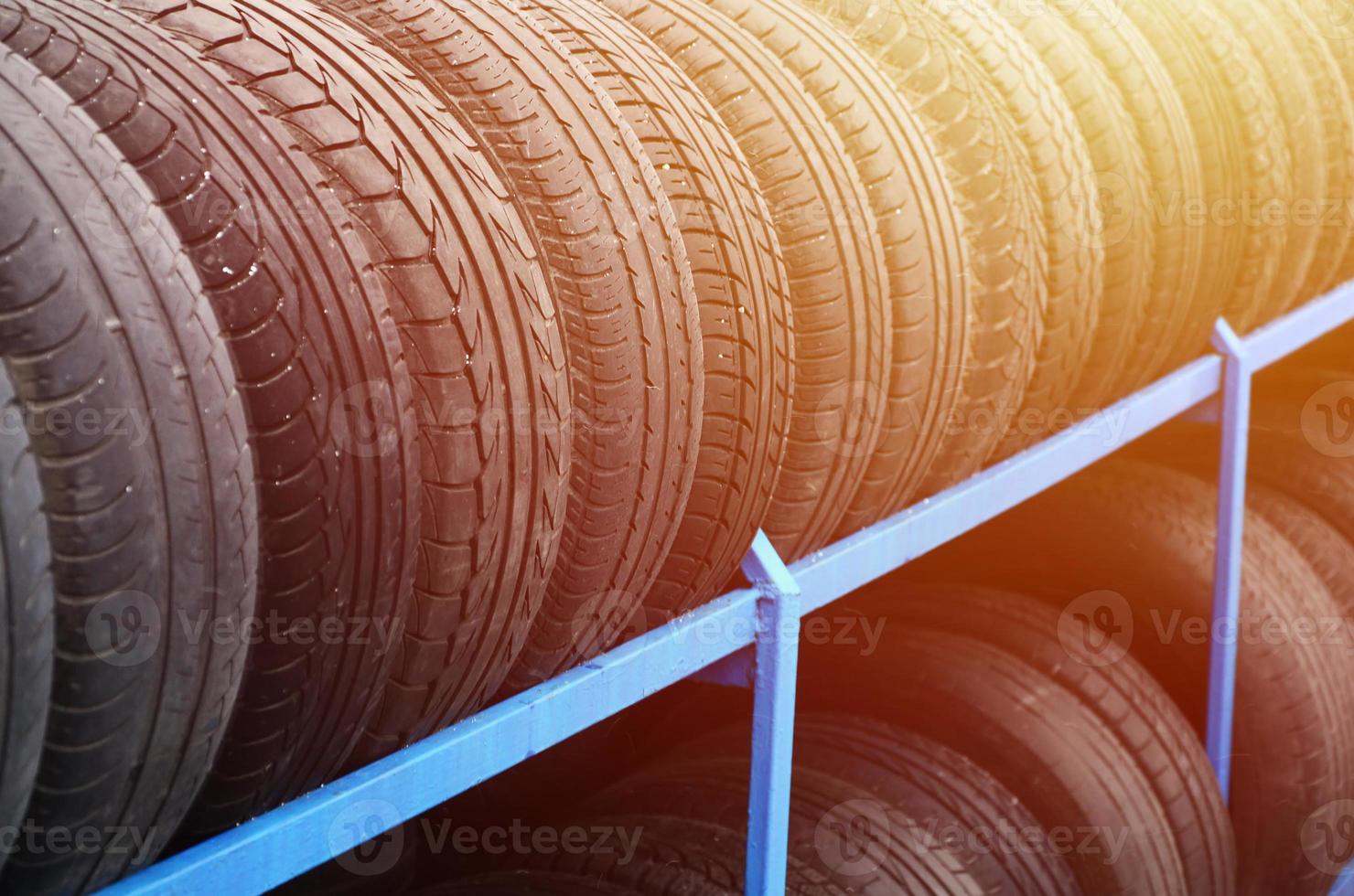 Rack with variety of car tires in automobile store. Many black tires. Tire stack background. Selective focus photo