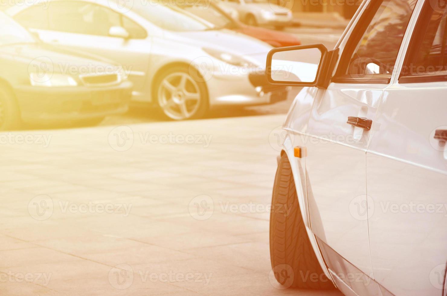 vista diagonal de un coche blanco brillante que se encuentra en un cuadrado de baldosas grises foto