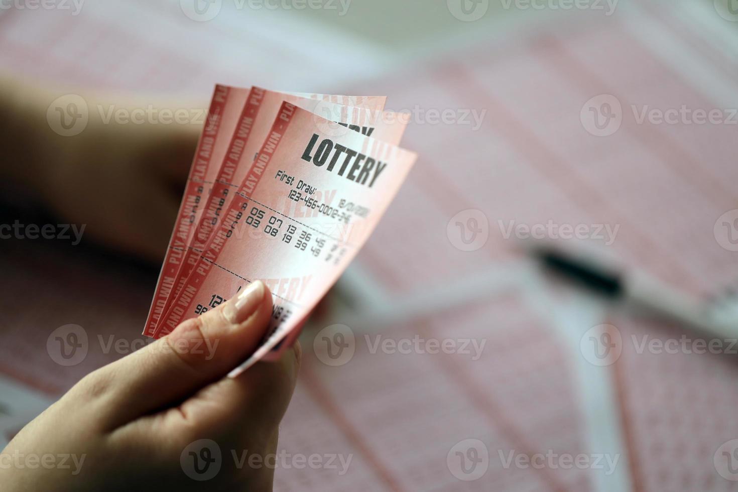 llenando un boleto de lotería. una mujer joven sostiene el billete de lotería con una fila completa de números en el fondo de las hojas en blanco de la lotería. foto