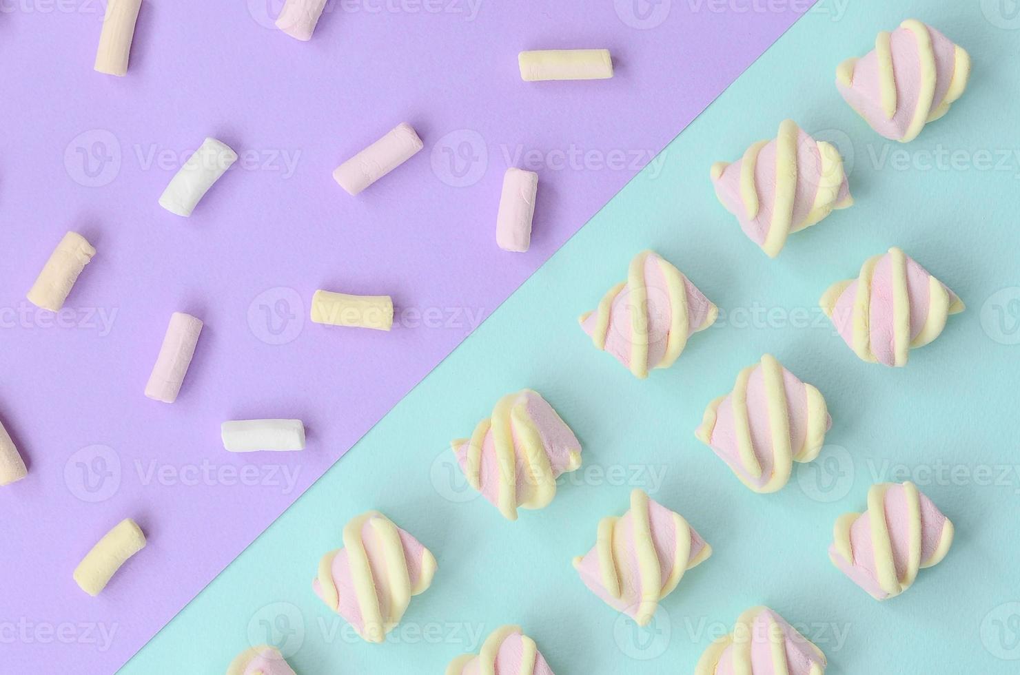 Colorful marshmallow laid out on violet and blue paper background. pastel creative textured pattern. minimal photo