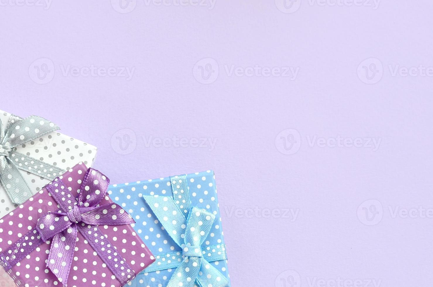 Pile of a small colored gift boxes with ribbons lies on a violet background. Minimalism flat lay top view photo