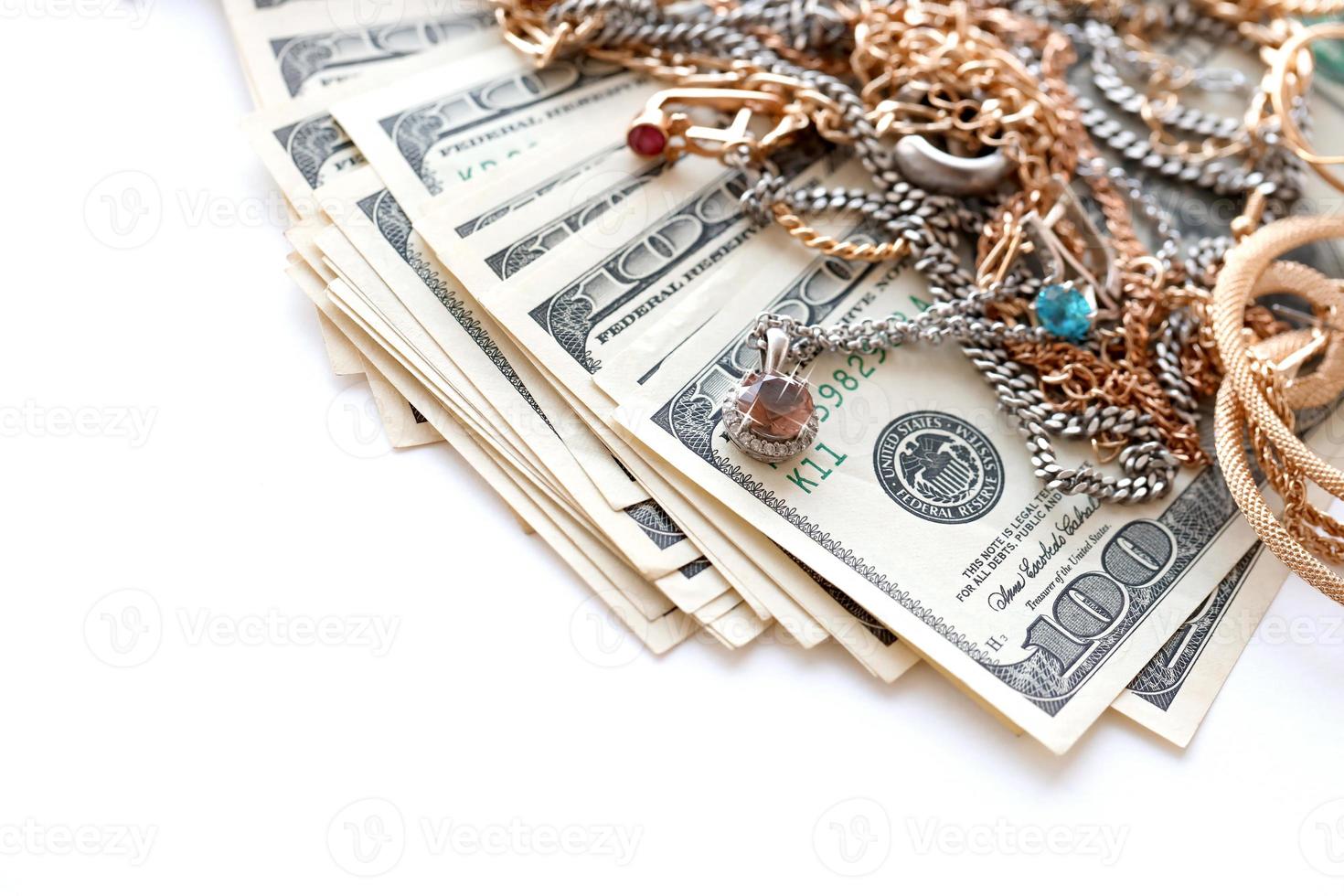 Many expensive golden and silver jewerly rings, earrings and necklaces with big amount of US dollar bills on white background. Pawnshop or jewerly shop photo