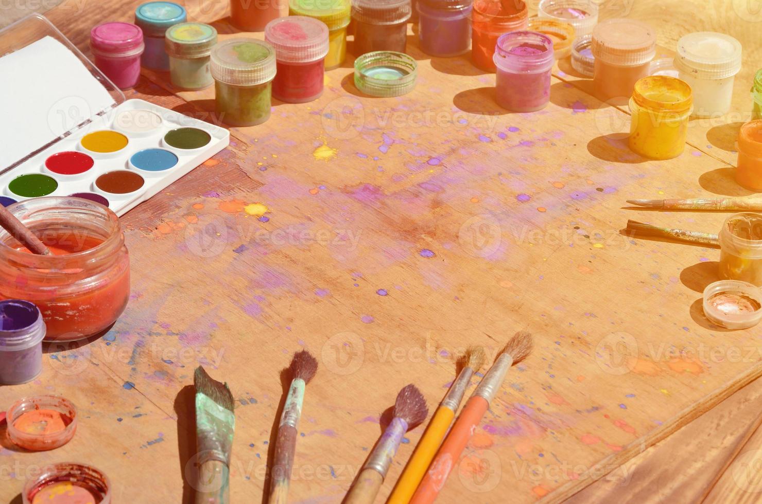Still life with a lot of brushes and jars of watercolor and gouache paint photo