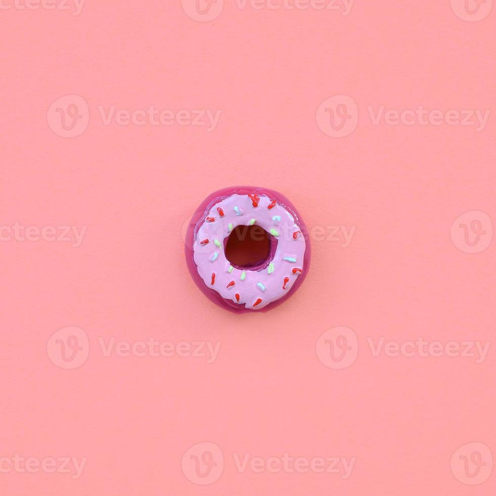 un solo donut de plástico pequeño se encuentra sobre un fondo de colores pastel. composición mínima plana. vista superior foto