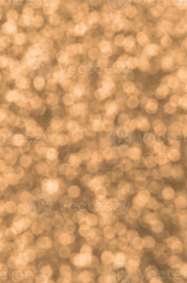 Blurred orange decorative sequins. Background image with shiny bokeh lights from small elements photo