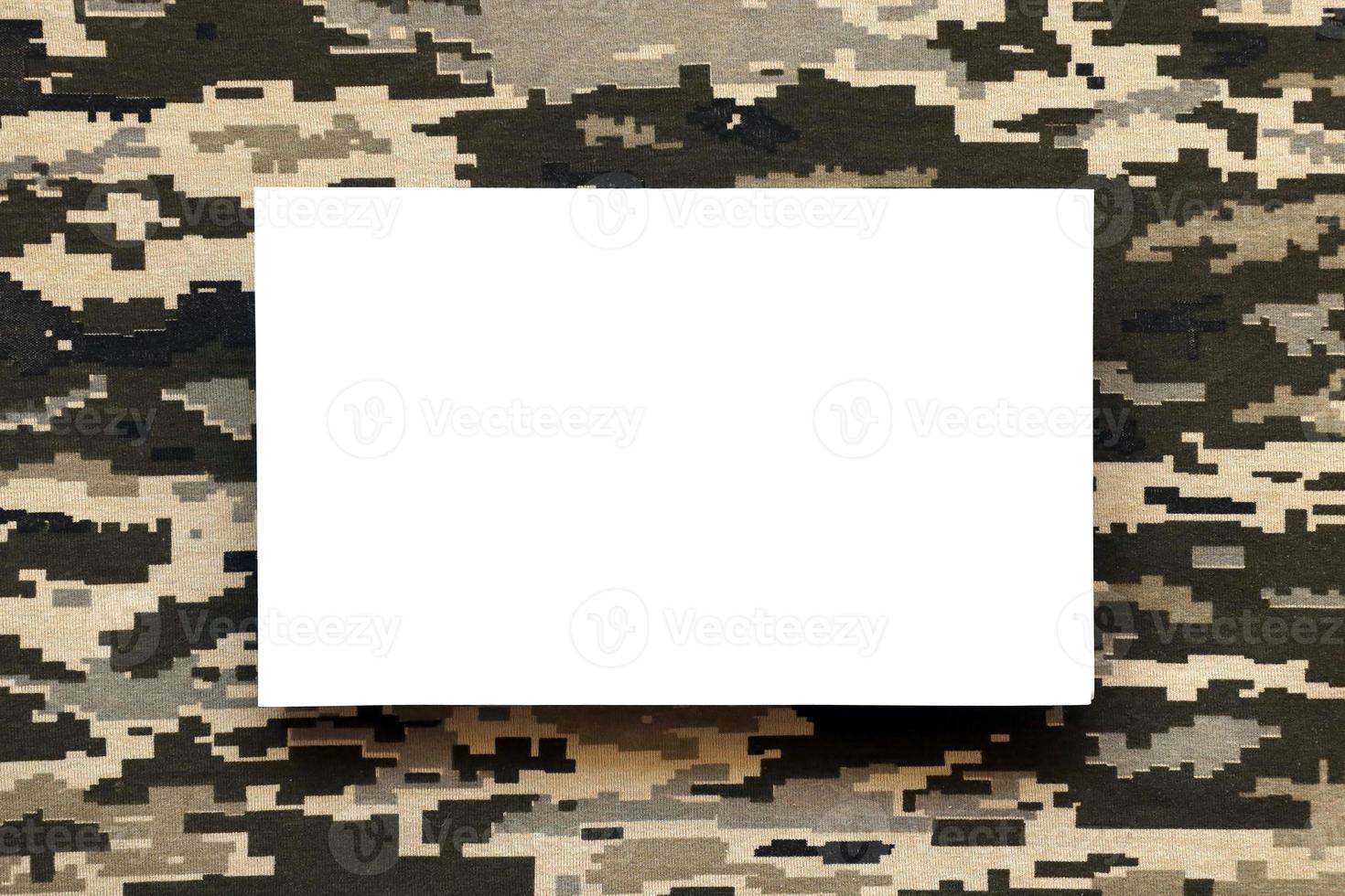 Fabric with texture of Ukrainian military pixeled camouflage and white blank paper. Cloth with camo pattern in grey, brown and green pixel shapes. photo