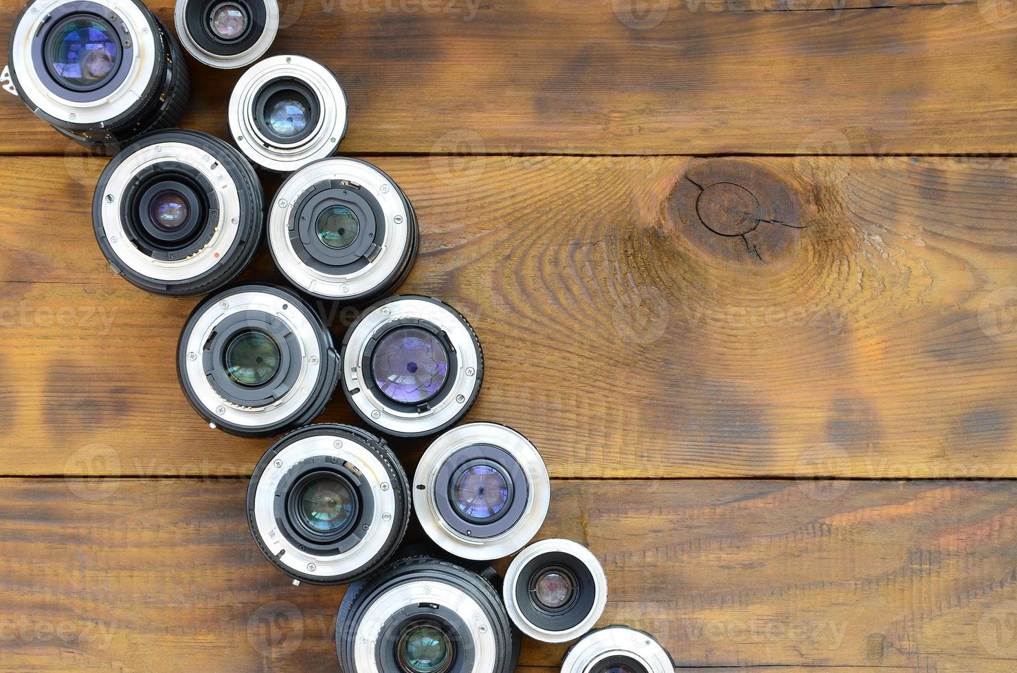 varias lentes fotográficas yacen sobre un fondo de madera marrón. espacio para texto foto