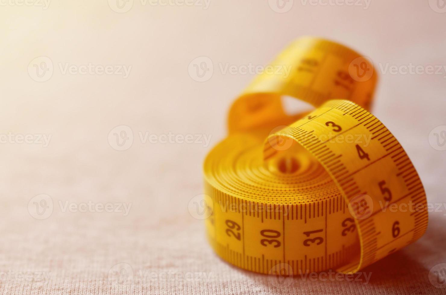 Yellow measuring tape lies on a gray knitted fabric photo