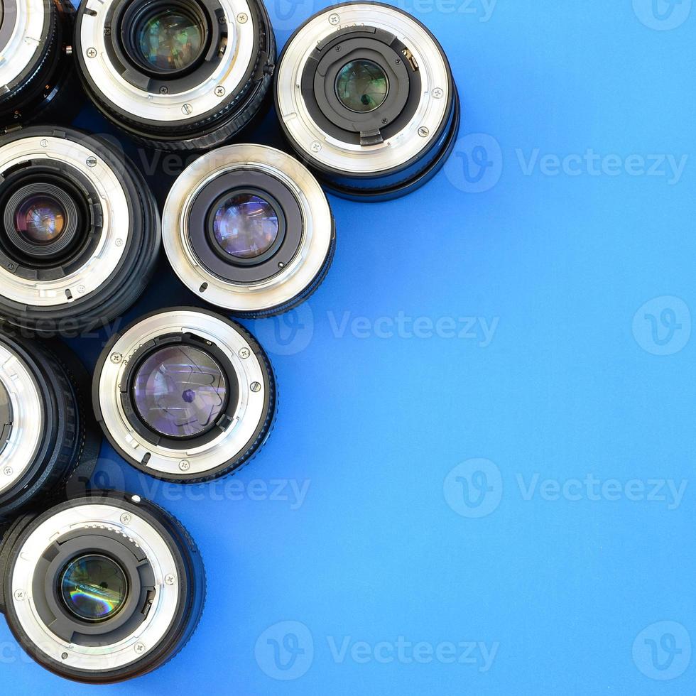 Several photographic lenses lie on a bright blue background. Space for text photo