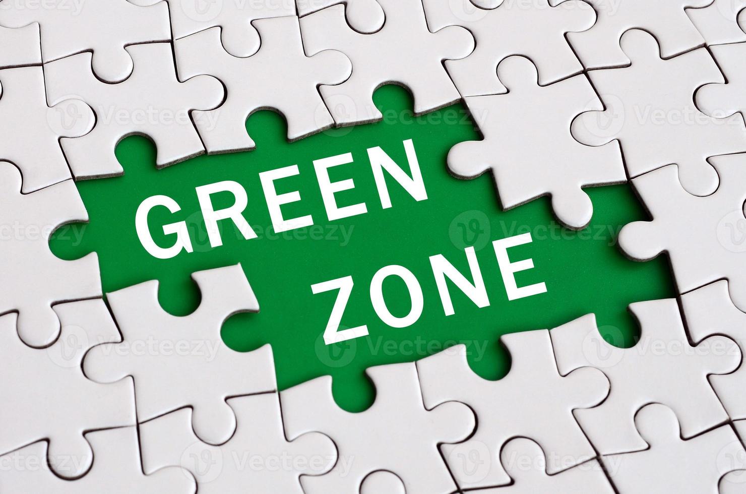 White jigsaw puzzle in assembled state with missing elements forming a green space with white inscription. Green zone photo