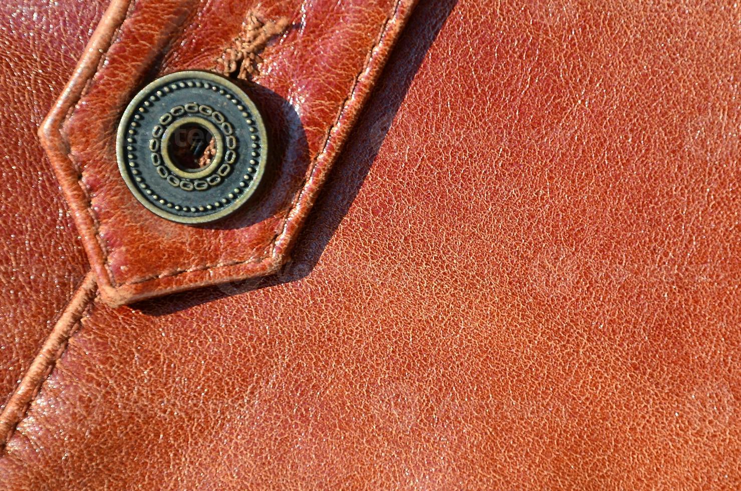 Brown leather texture. Useful as background for any design work. Macro photo of a button on outer clothing made of genuine leather