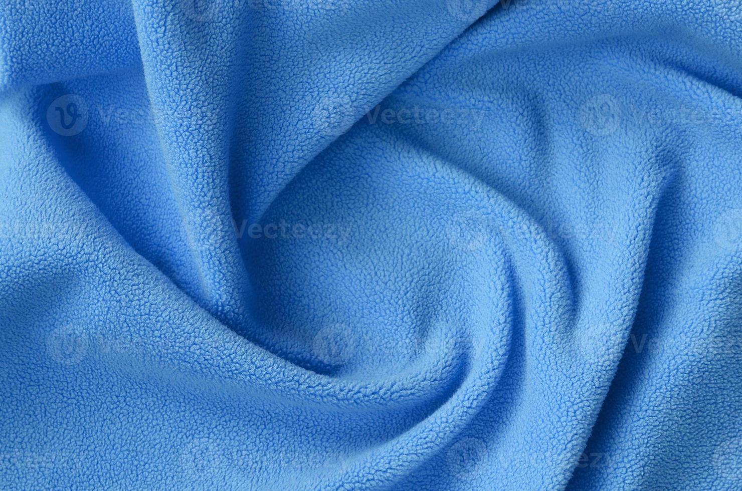 The blanket of furry blue fleece fabric. A background of light blue soft plush fleece material with a lot of relief folds photo