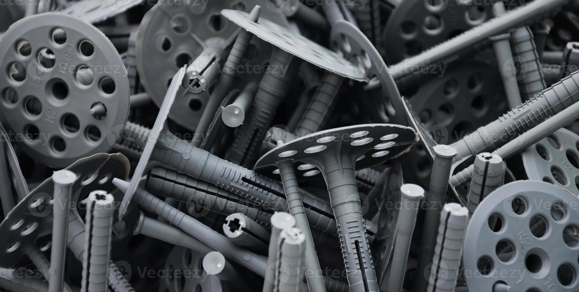 Background pattern of many gray plastic dowels fastening for thermal insulation. A huge pile of fixtures for the installation of expanded polystyrene plates for the insulation of the building walls photo