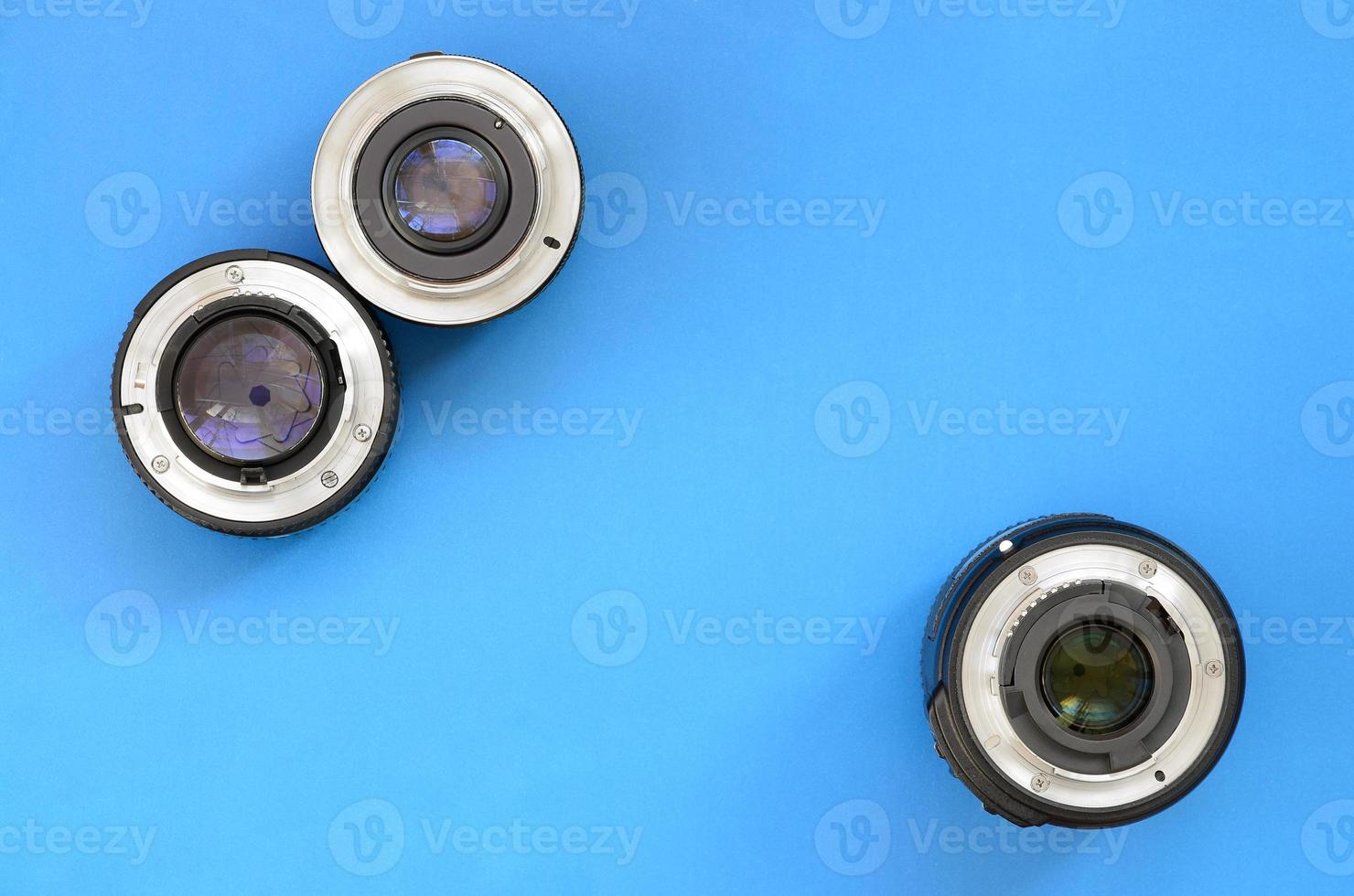 Several photographic lenses lie on a bright blue background. Space for text photo