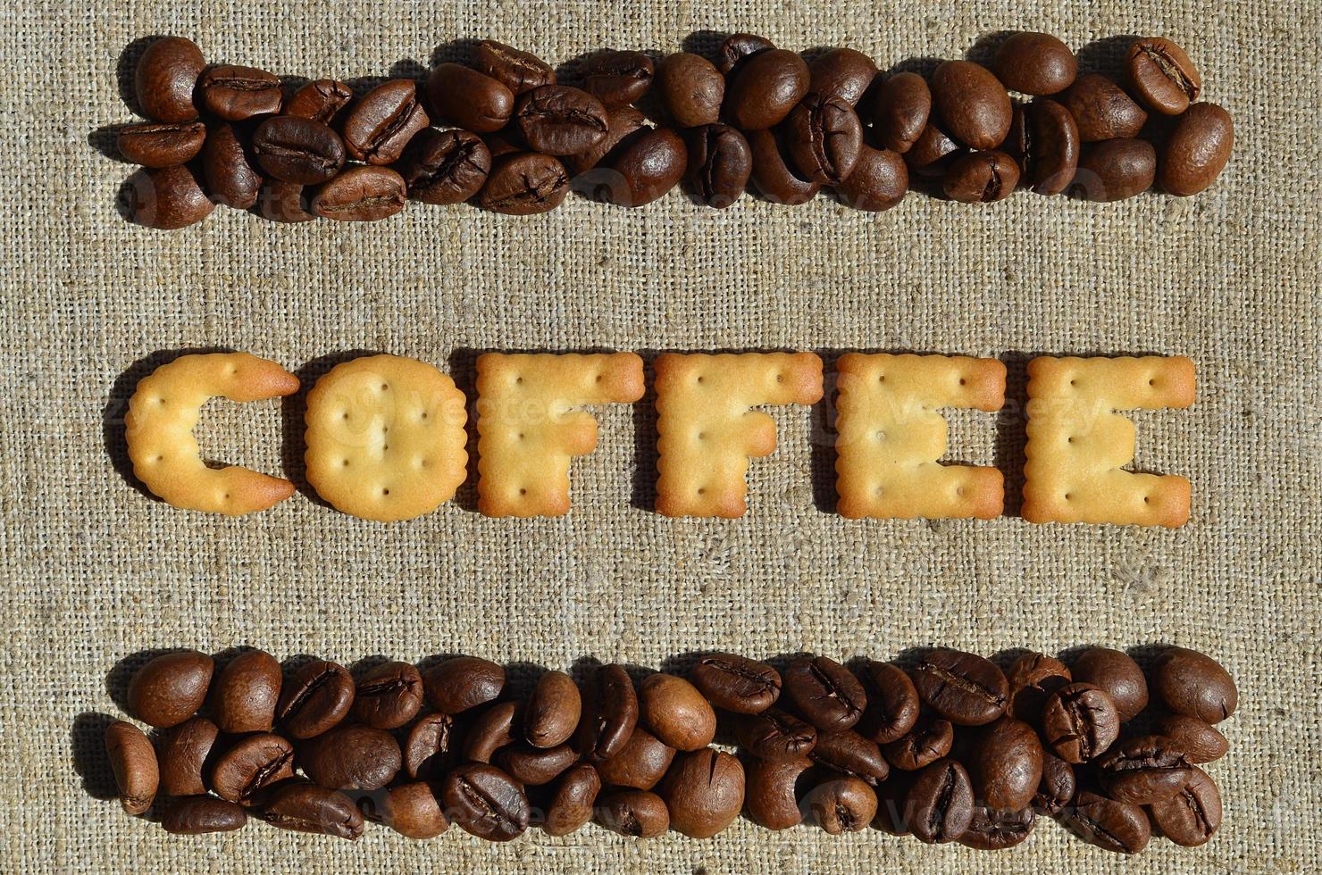 Coffee. The word from the edible letters lies on the gray canvas with coffee beans photo