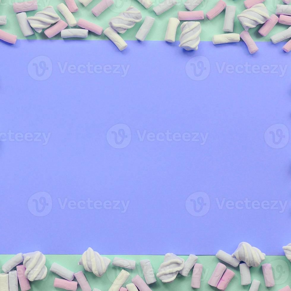 Colorful marshmallow laid out on green and lilac paper background photo