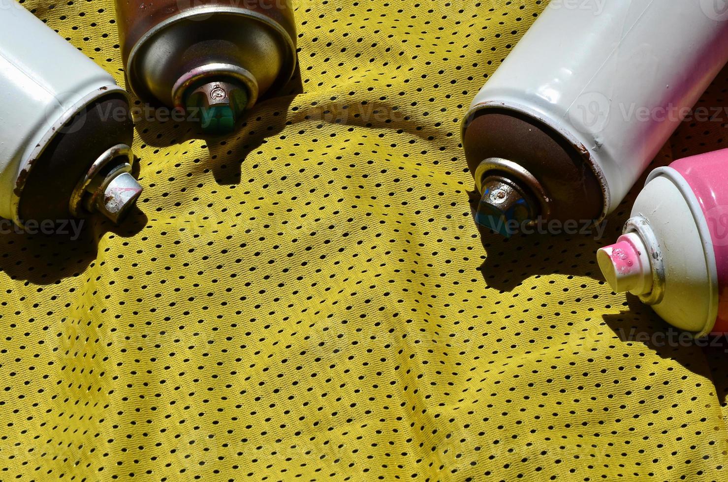 Several used aerosol paint sprayers lie on the sports shirt of a basketball player made of polyester fabric. The concept of youth street art, active sports and eventful lifestyle photo