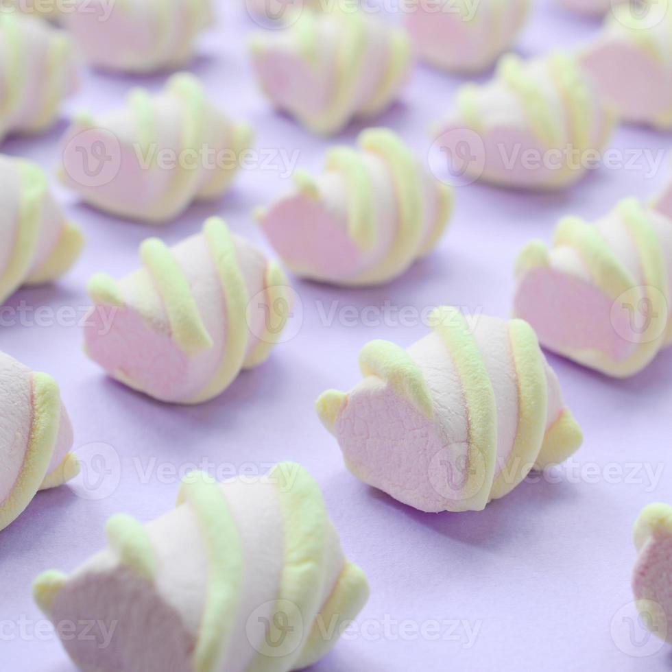 Colorful marshmallow laid out on violet paper background. pastel creative textured pattern. Perspective macro shot photo