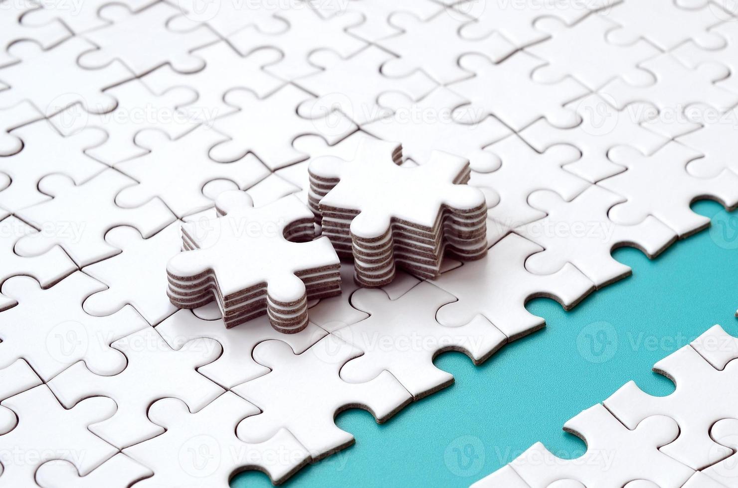 The blue path is laid on the platform of a white folded jigsaw puzzle. The missing elements of the puzzle are stacked nearby. Texture image with space for text photo