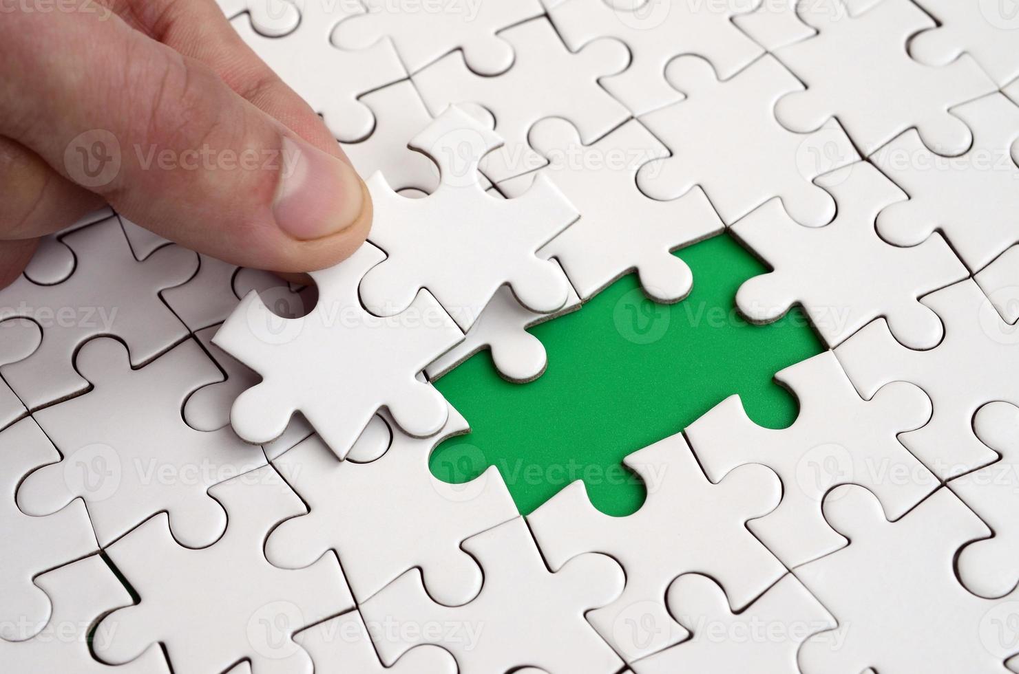 The human hand fills the last missing elements of the surface from the jigsaw puzzle. The concept of the completion of the initiated cases photo