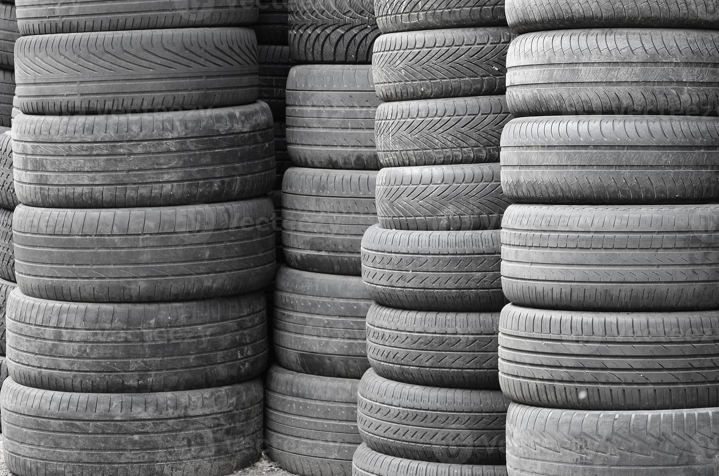 Old used tires stacked with high piles in secondary car parts shop garage photo