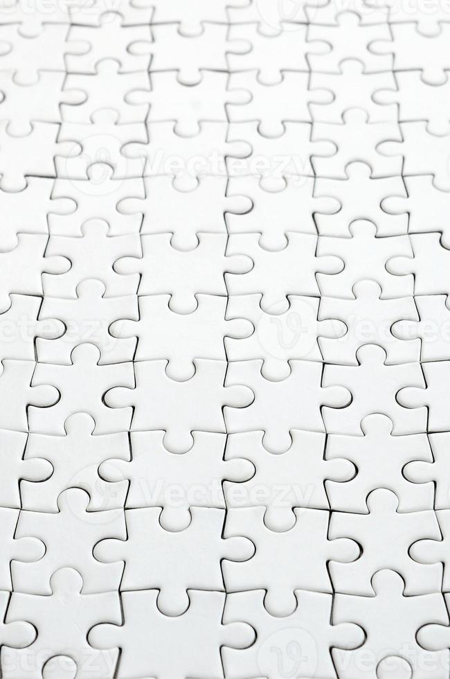 Close up of a white jigsaw puzzle in assembled state in perspective. Many components of a large whole mosaic are united photo