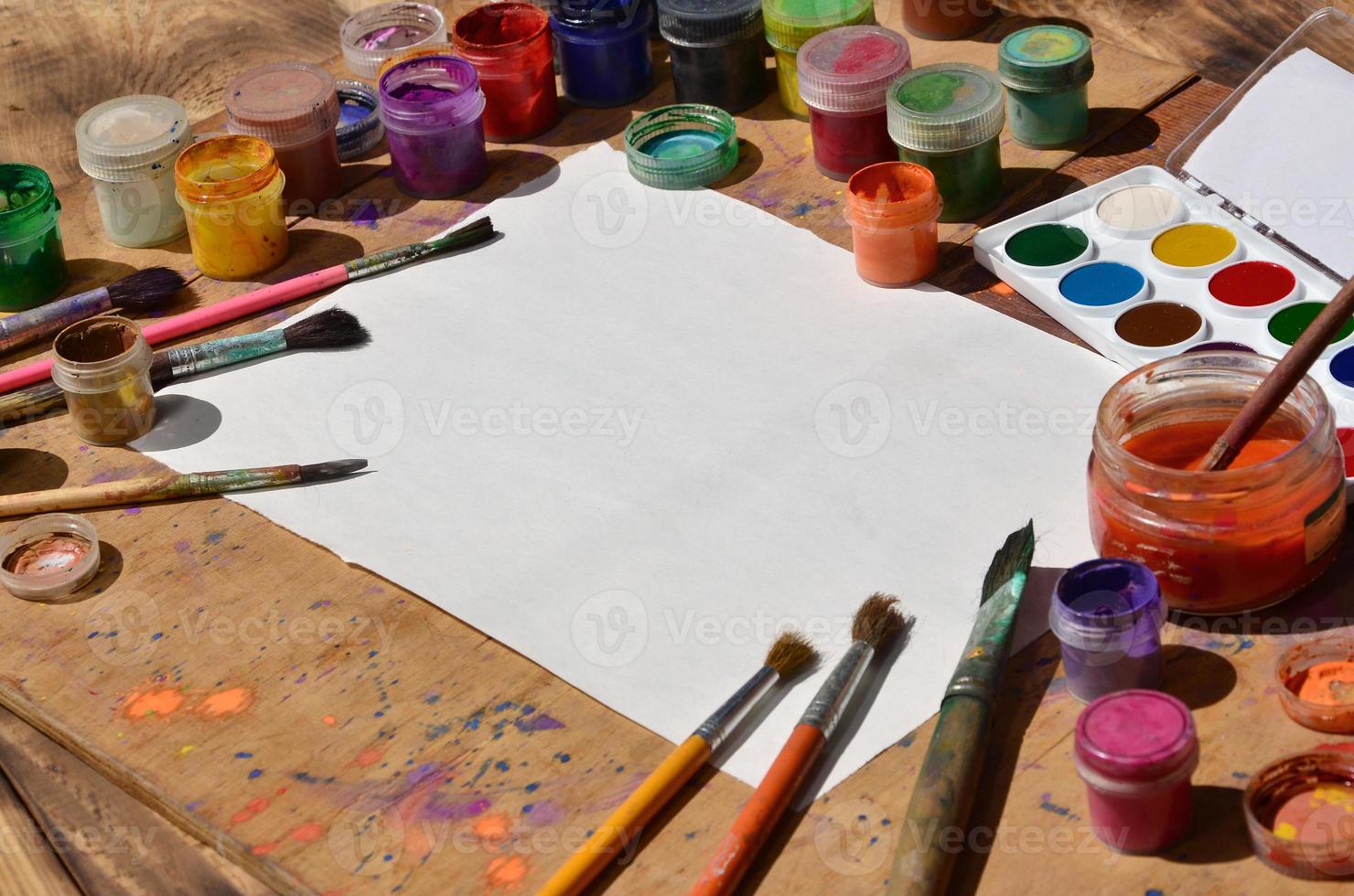 Still life with blank paper, brushes and jars of watercolor and gouache paint photo