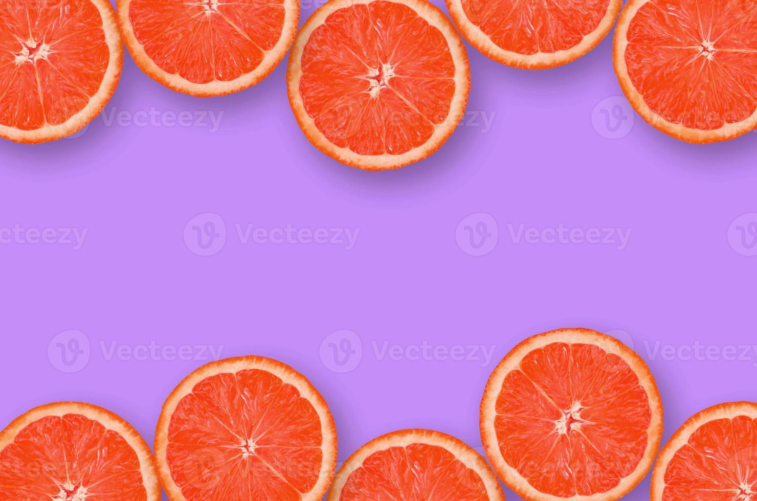 Frame of grapefruit citrus slices on bright purple background photo