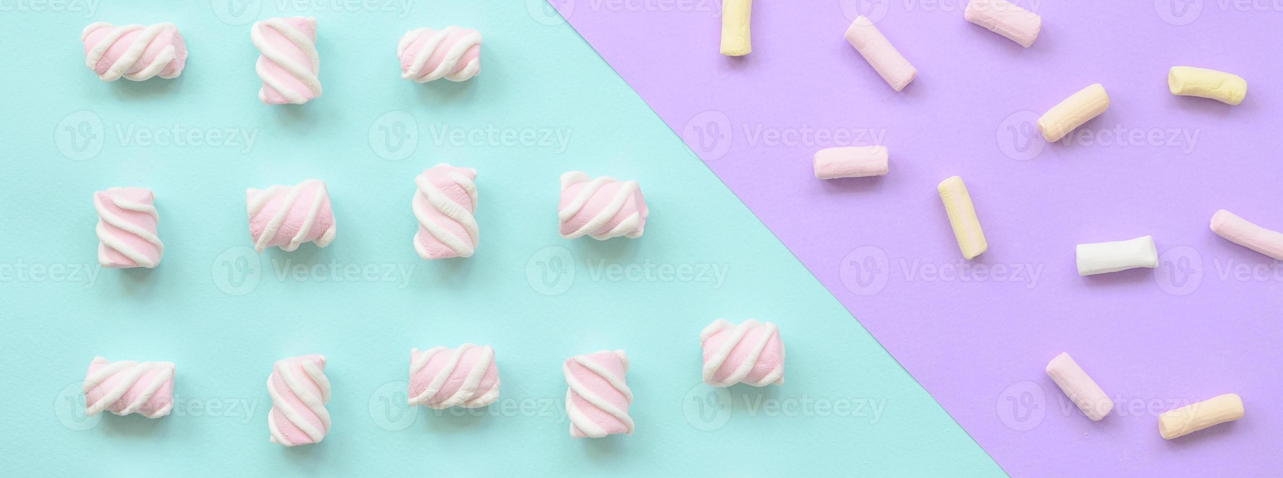 Colorful marshmallow laid out on violet and blue paper background. pastel creative textured pattern. minimal photo