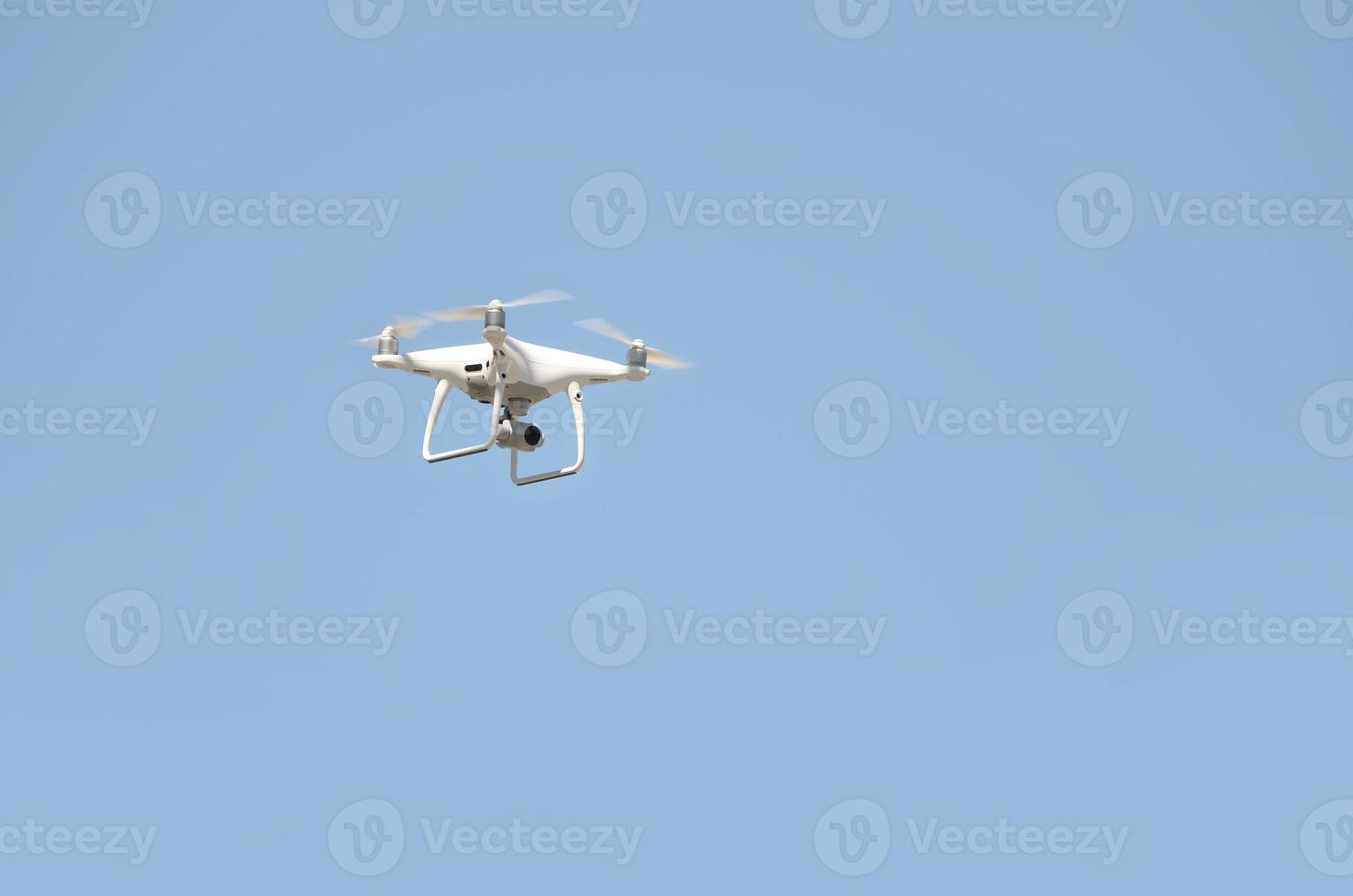 Big white drone hovering in a bright cloudless blue sky photo