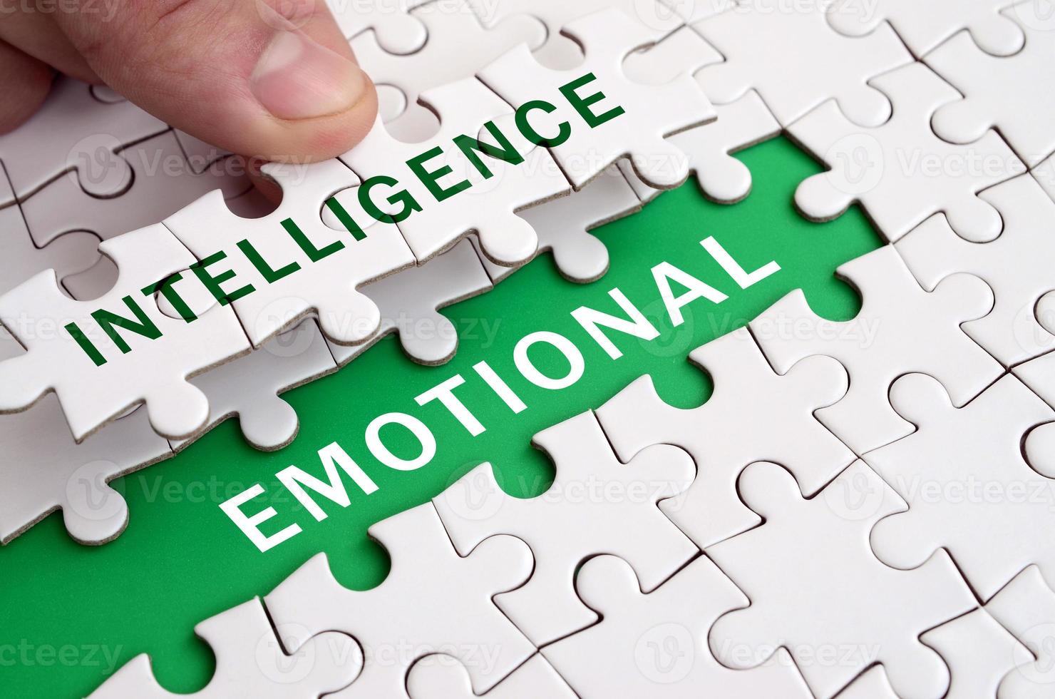 The human hand fills the last missing elements of the surface from the jigsaw puzzle. Image with words intelligence and emotional photo
