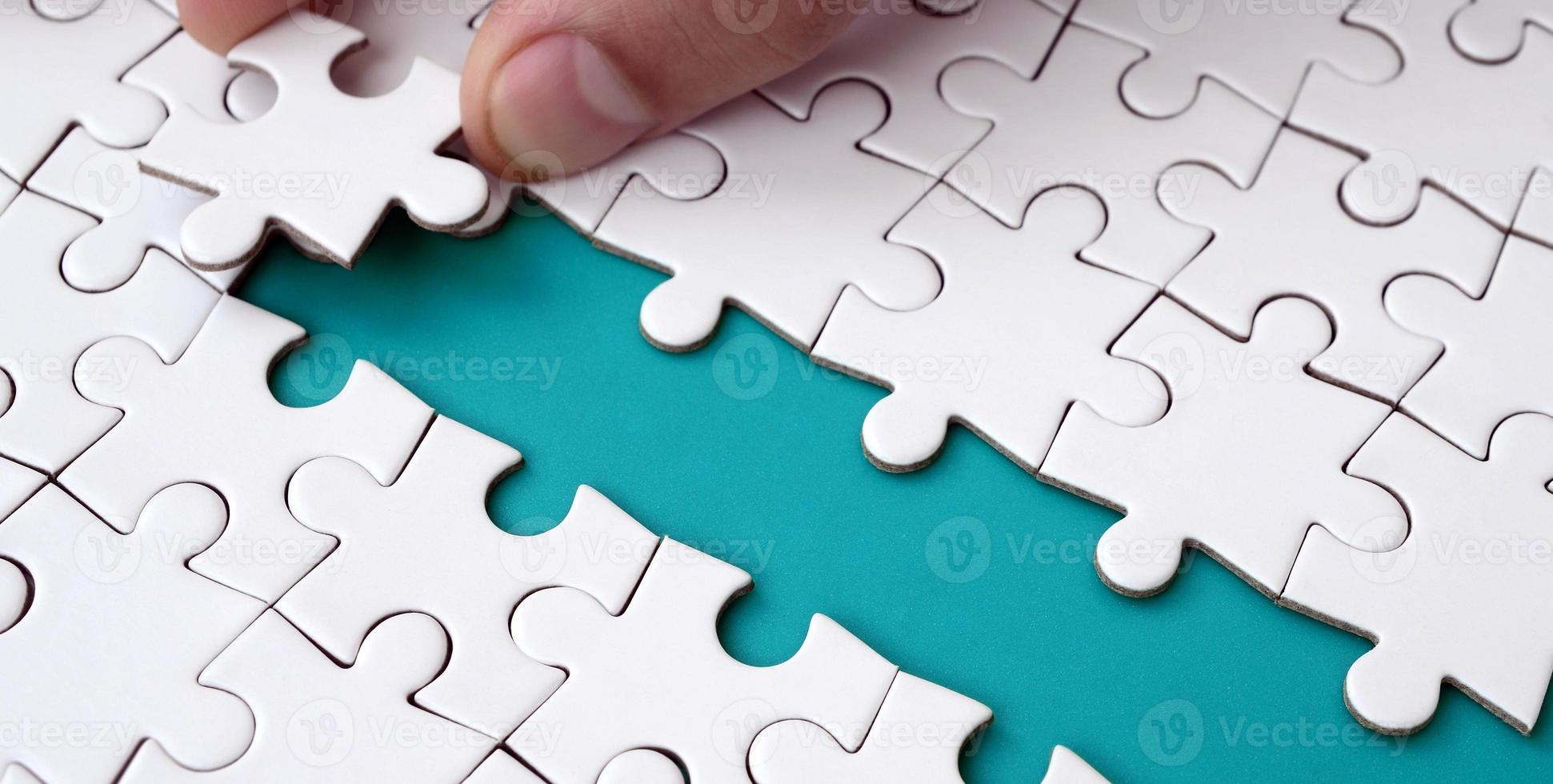 The human hand paves the way to the surface of the jigsaw puzzle, forming a blue space. The concept of overcoming the difficulties on the way to success photo