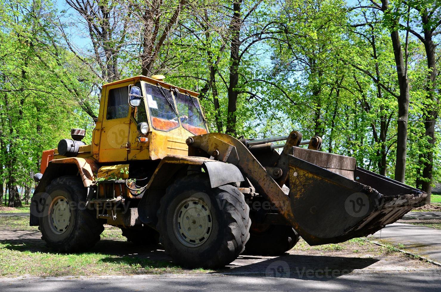The city improvement team removes the fallen leaves in the park with an excavator and a truck. Regular seasonal work on improving the public places for recreation photo