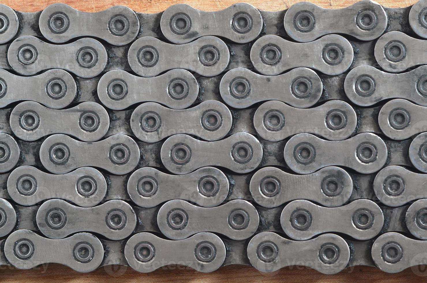 Dirty and oily chain from a mountain bike lying on a wooden table in a bicycle shop photo