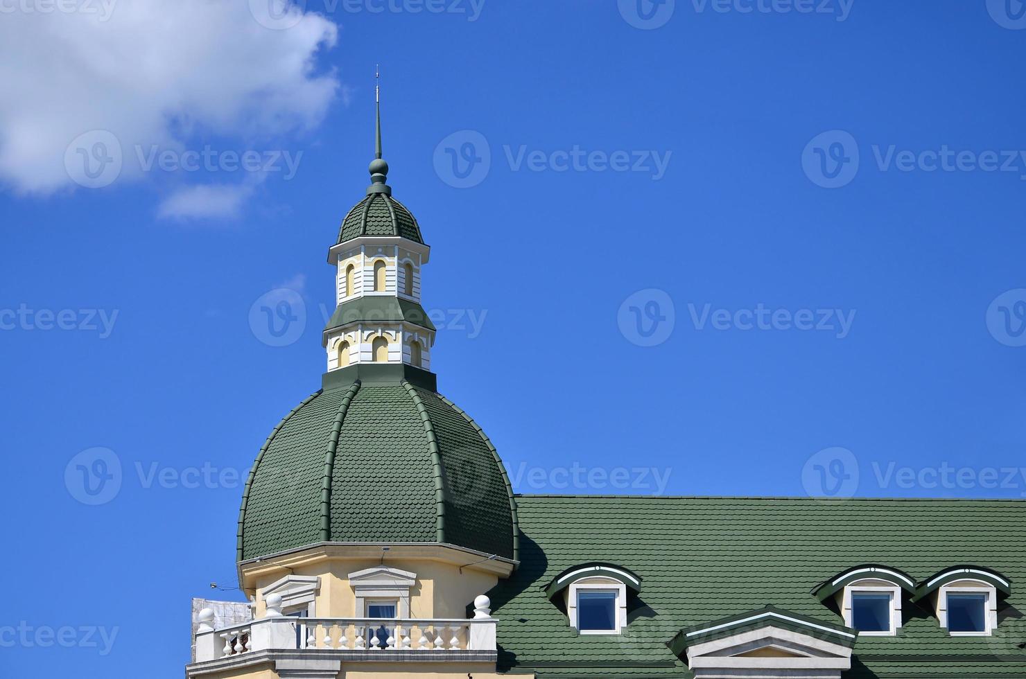 Completed perfect high-quality roofing work from metal roofing. The dome of a polyhedral shape with a spire is covered with green metal tiles photo