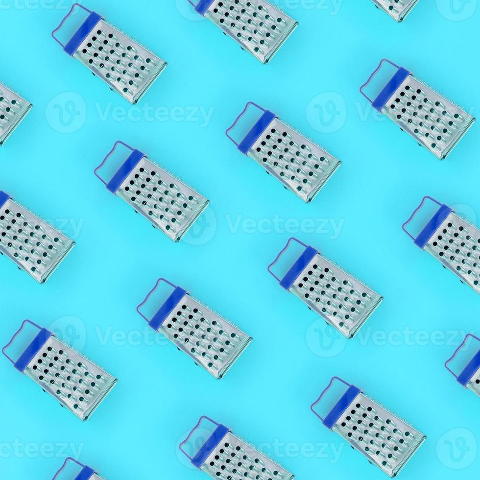 Small stainless steel graters lies on a pastel colored paper. Kitchen accessories. Tools for cooking. Flat lay top view photo