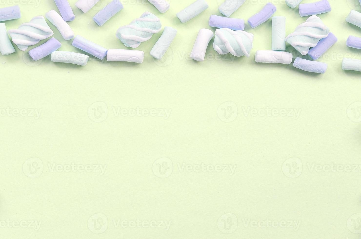 Colorful marshmallow laid out on lime paper background. pastel creative textured framework photo
