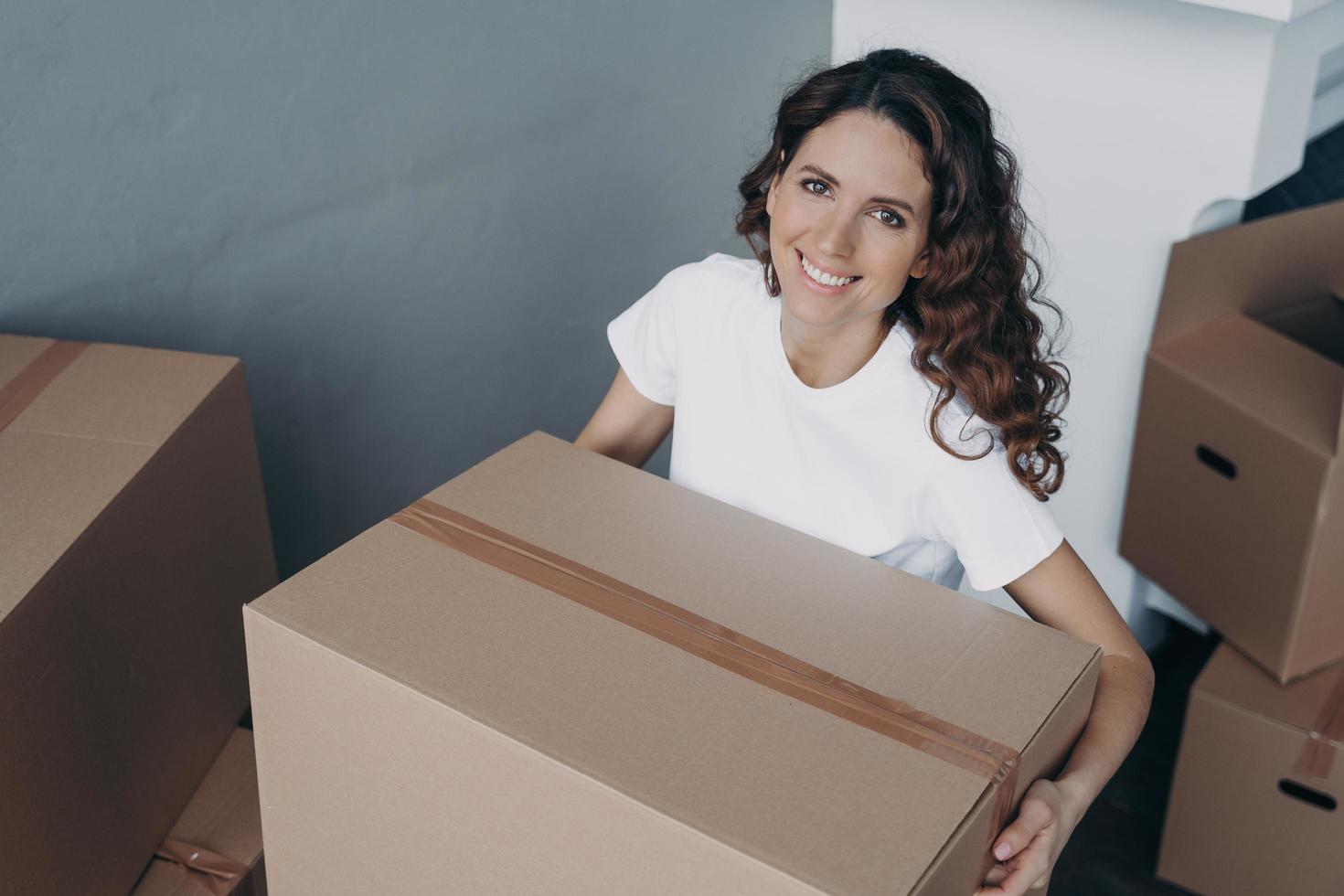 Smiling woman holds cardboard box parcel. Easy relocation. Advertising of moving or delivery service photo
