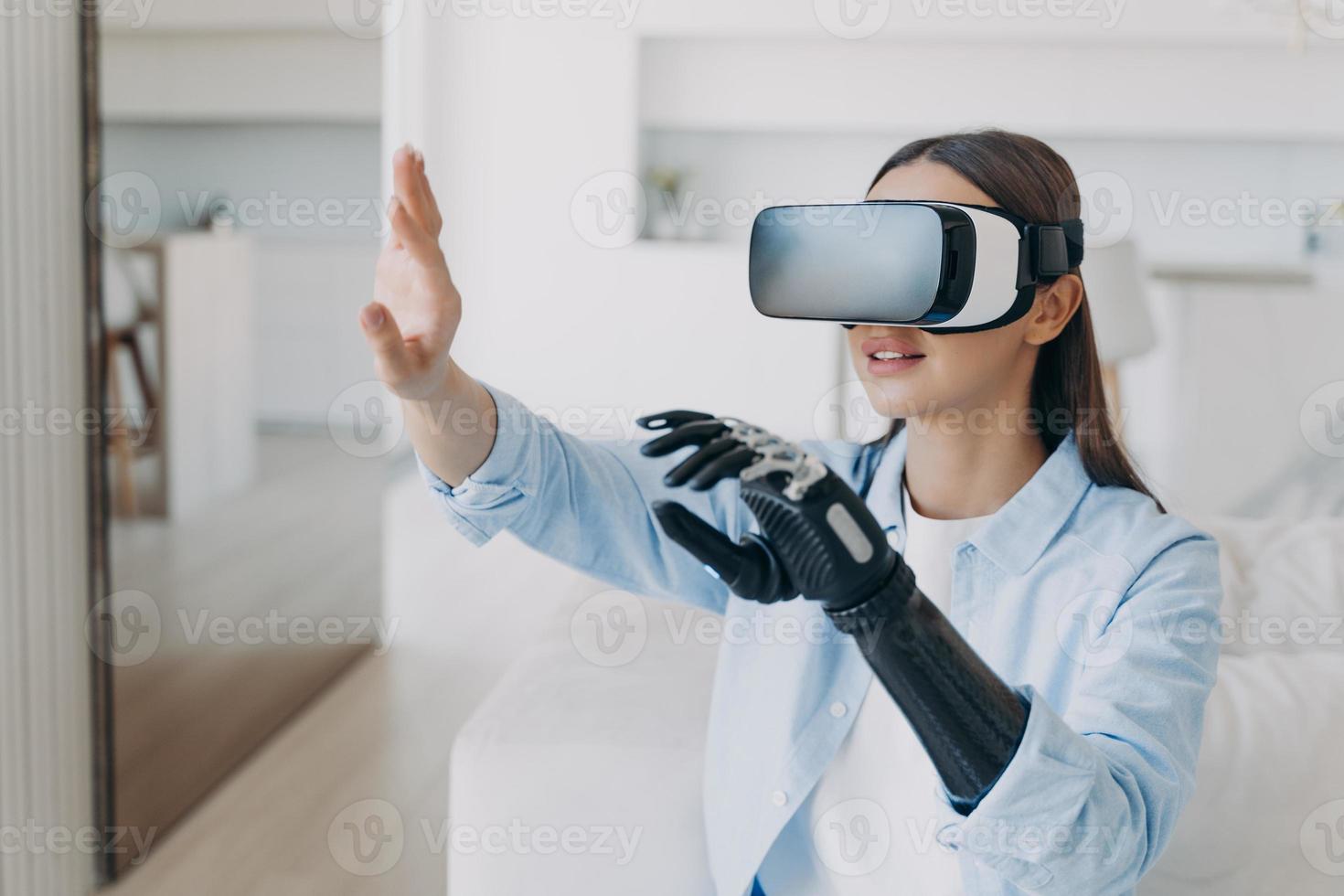 Disabled girl wearing virtual reality glasses with bionic prosthetic arm gets rehabilitation