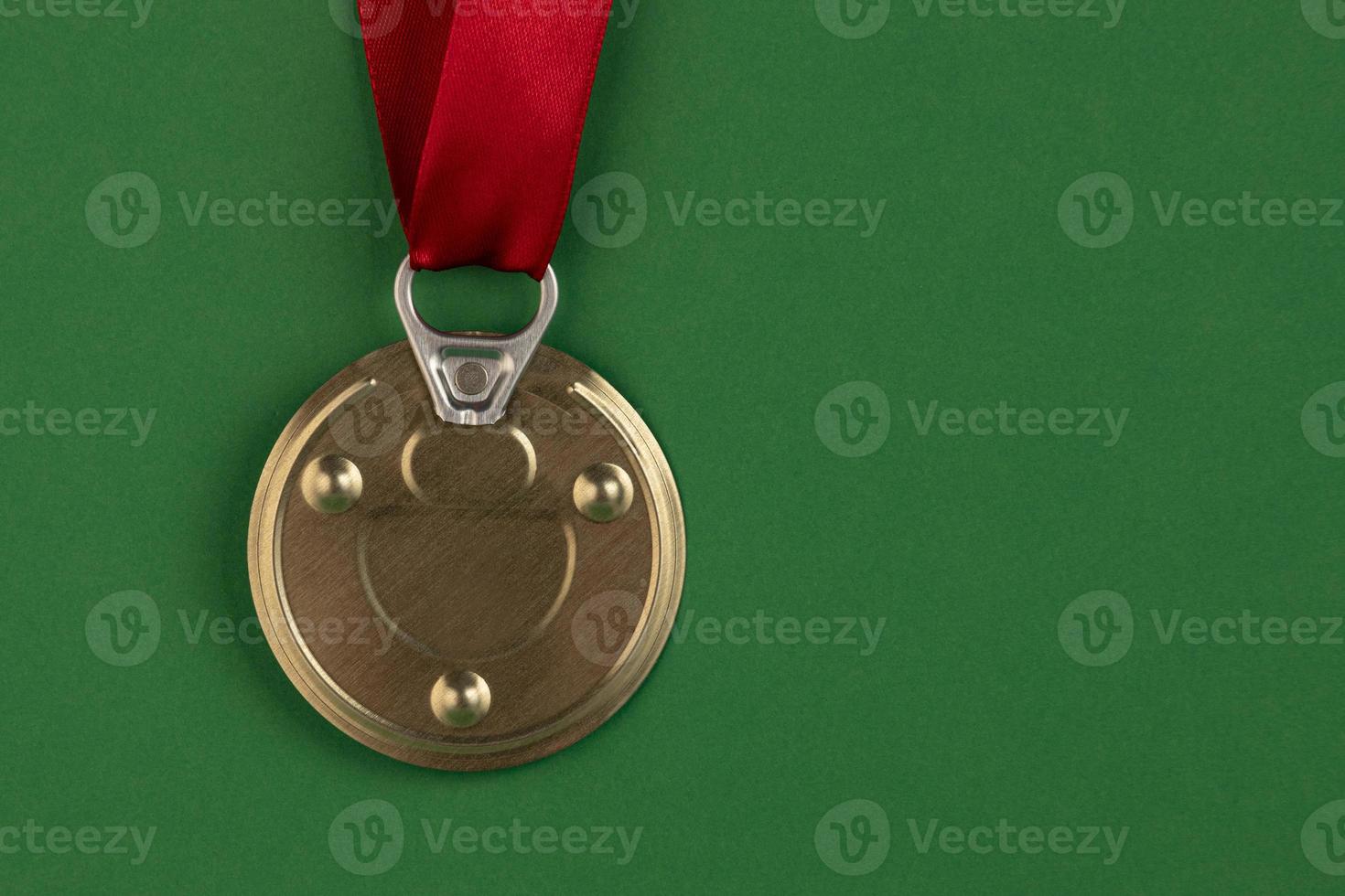 la medalla está hecha de una tapa de lata con una cinta de premio roja sobre un fondo verde. antimedalla foto