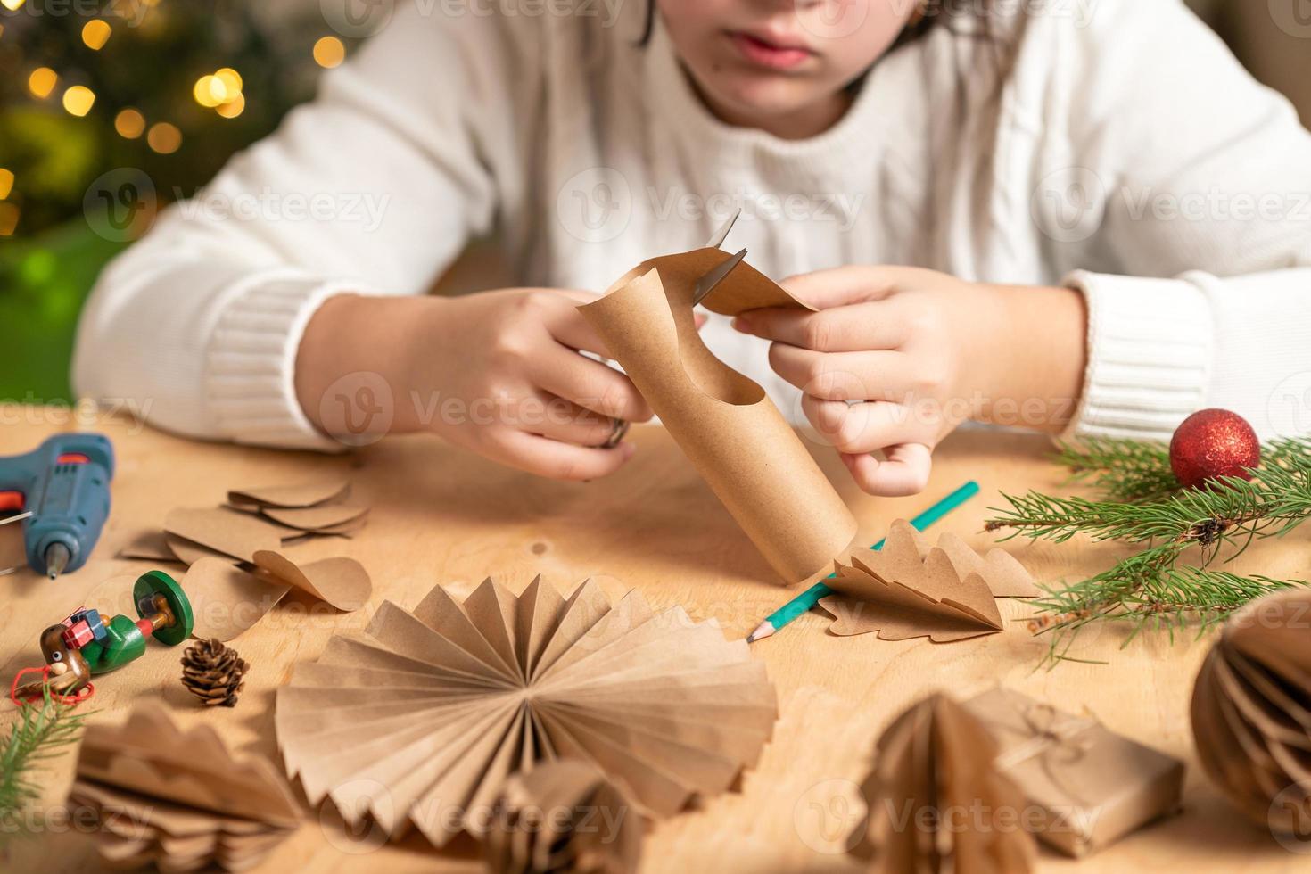 la niña hace decoraciones para árboles de navidad con papel con sus propias manos. paso 2 foto