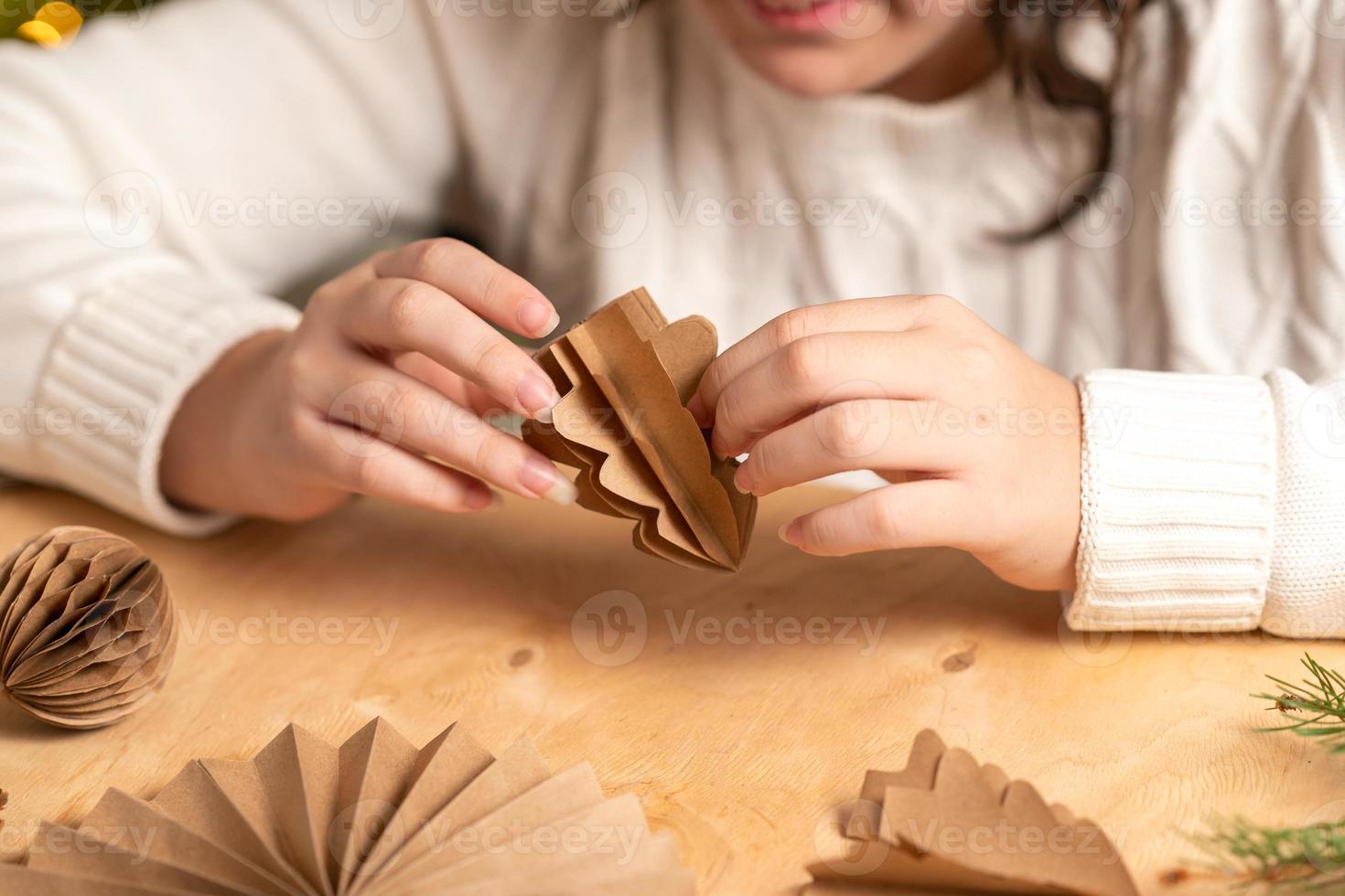 girl makes Christmas tree decorations out of paper with her own hands. step 5. step-by-step instruction photo