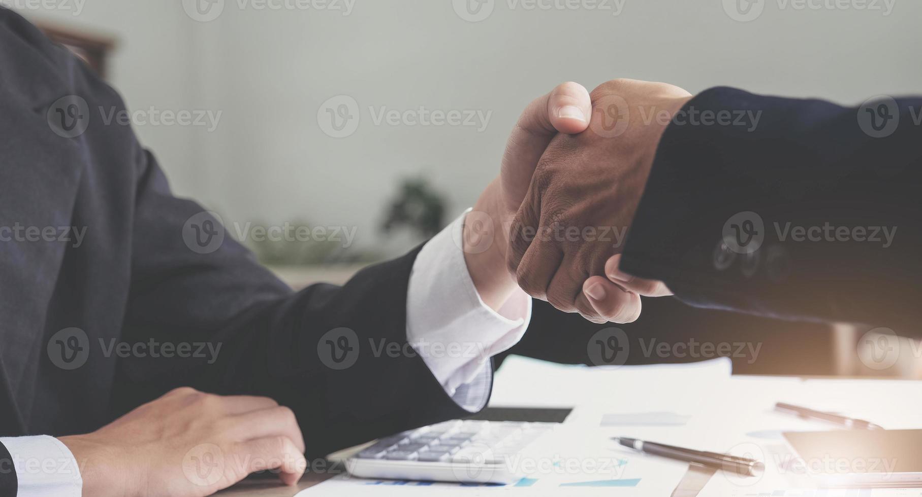 dos hombres de negocios confiados dándose la mano durante una reunión en la oficina, el éxito, el trato, el saludo y el concepto de socio. foto