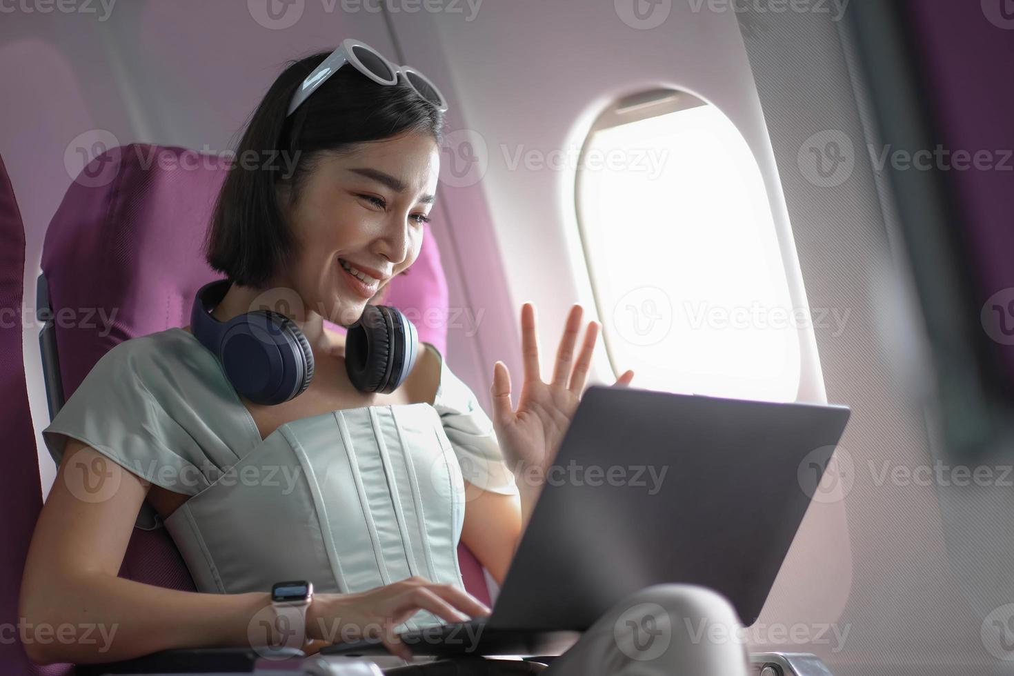 Asian young woman using laptop sitting near windows at first class on airplane during flight,Traveling and Business concept photo