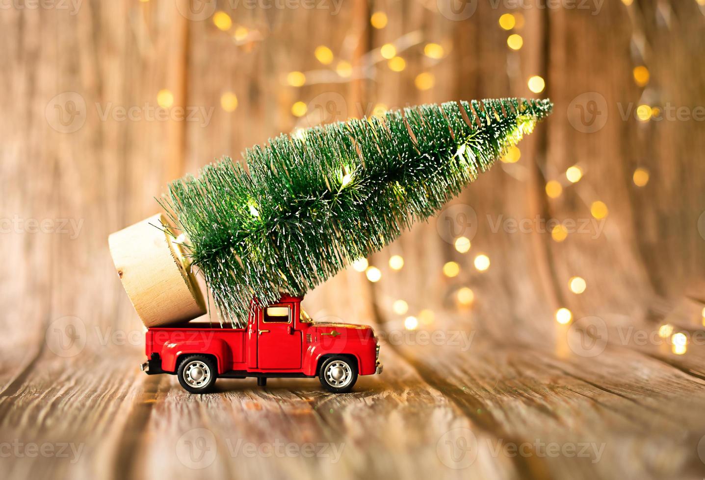 miniature car on wooden background with christmas light, holiday gift. photo
