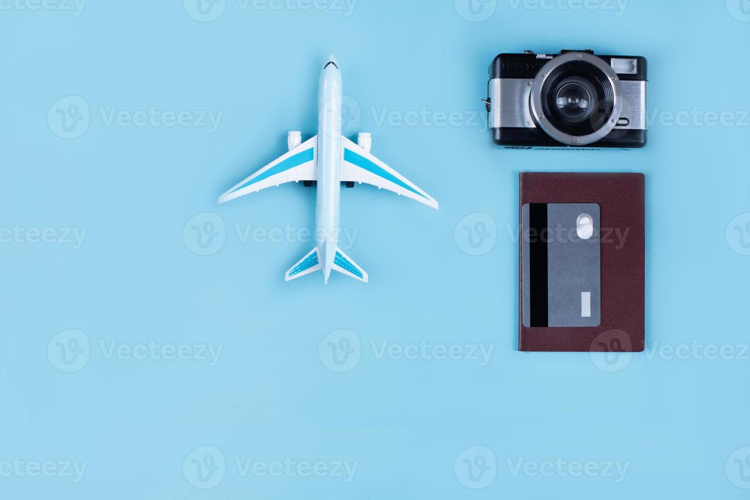 miniatura de avión como símbolo de viaje. cámara y pasaporte, accesorios de viaje, tarjeta de crédito para pagar una estancia confortable. foto