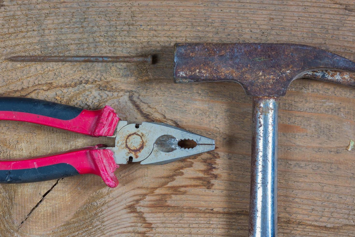 Diferentes herramientas en un fondo de madera. clavos, martillo, alicates foto