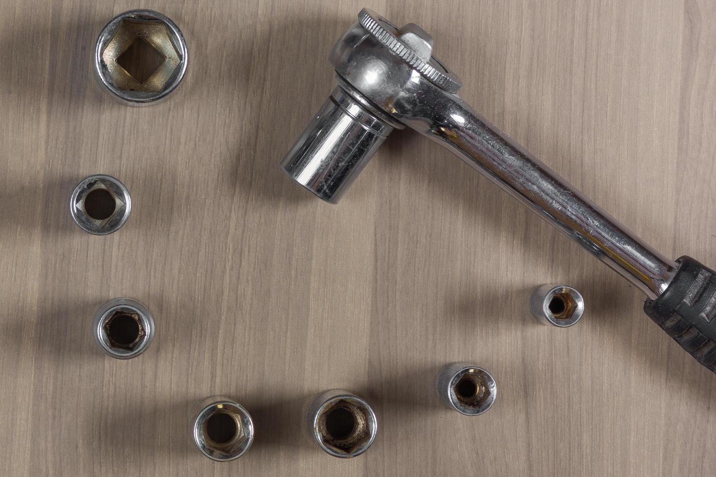 Different tools on a wooden background. Collapsible wrench with interchangeable heads photo