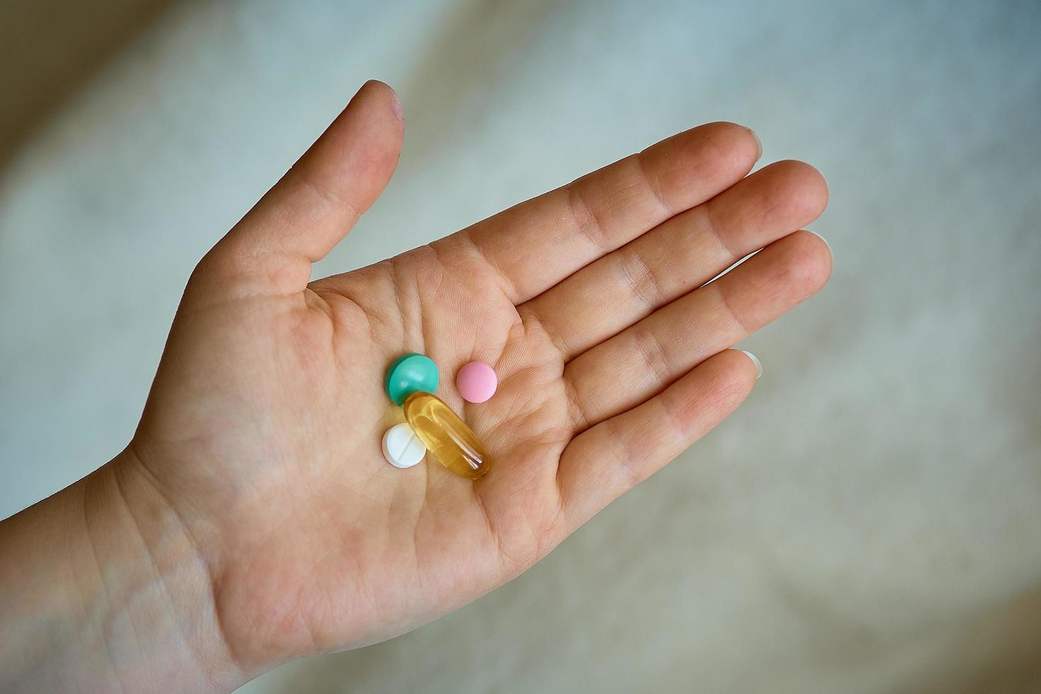 holds a pill in her hand, headache and cold photo