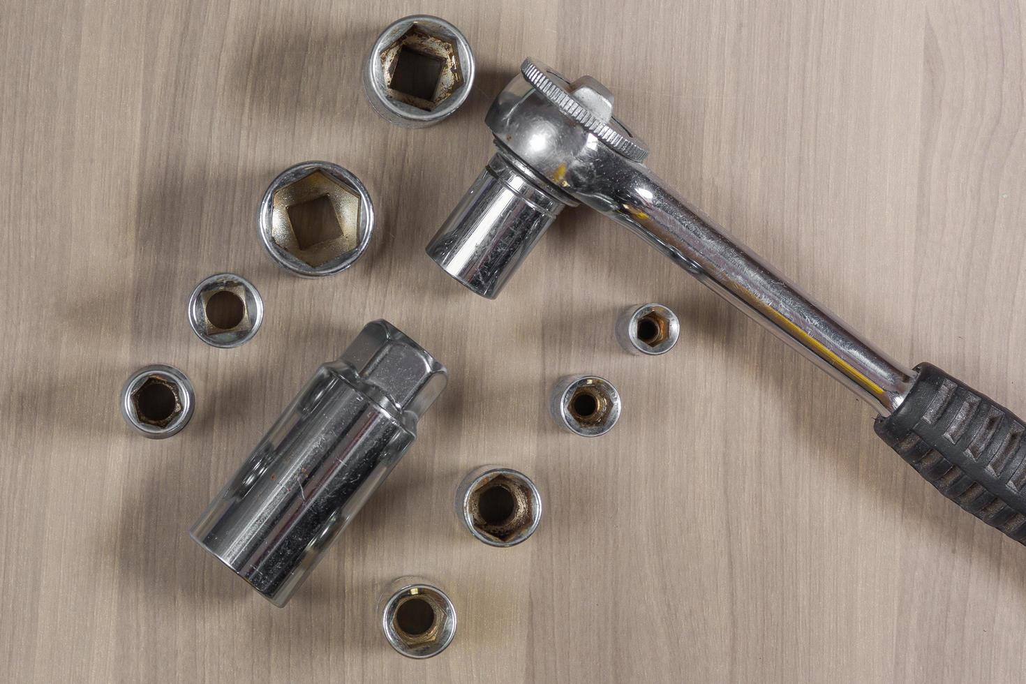 Different tools on a wooden background. Collapsible wrench with interchangeable heads photo